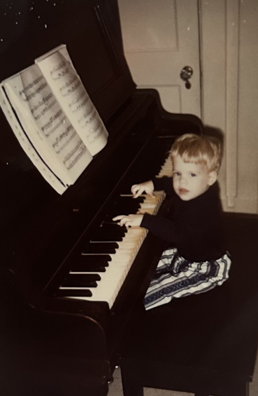 Dave as a small child at an upright piano.