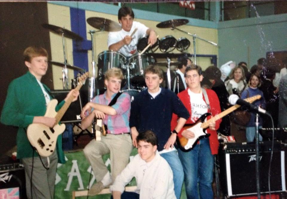 Sasquatch set up on stage in a school gym, with a crowd behind them.